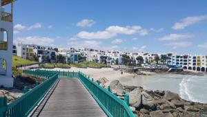 a boardwalk leading to a beach with white buildings at Private Kaliva 605, Club Mykonos Resort in Langebaan