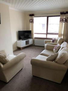 uma sala de estar com 2 sofás e uma televisão de ecrã plano em 10 Redcliffe em Stornoway