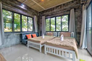 a bedroom with two beds and a couch and windows at Chill at Hill in Pak Chong