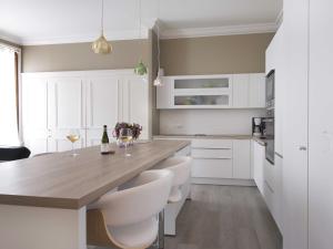 a kitchen with white cabinets and a wooden counter top at Sasha bel appartement renove centre ville Beaune in Beaune