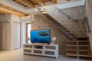 ein Wohnzimmer mit einem TV und einer Treppe in der Unterkunft Limestone Heritage House in Trogir