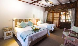 ein Hotelzimmer mit 2 Betten mit Blumen darauf in der Unterkunft Storms River Guest Lodge in Stormsrivier
