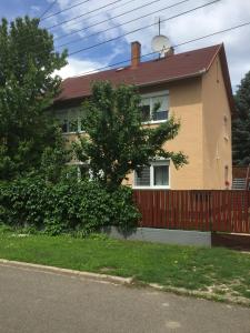 ein gelbes Haus mit einem Zaun und einem Baum in der Unterkunft Big Apartman in Hajdúszoboszló