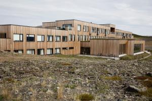 a building on a hill with a field at Fosshótel Mývatn in Myvatn