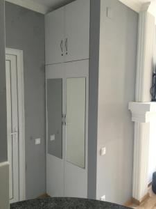 um quarto com armários brancos e um espelho em Apartment White Magnolia em Batumi