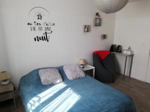 a bedroom with a bed with a blue blanket and a chair at Le petit nid douillet in Trescléoux