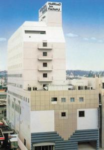 a tall white building with a sign on it at Marroad Inn Hachioji in Hachioji