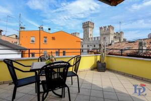 una mesa y sillas en un balcón con un castillo en Desenzanoloft Penthouse Never say Never Sirmione, en Sirmione