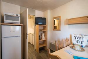 a small kitchen with a refrigerator and a table at Neige et Soleil in Montchavin