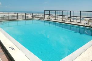 a large swimming pool with the beach in the background at Ocean Trillium Suites in New Smyrna Beach
