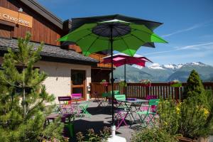 une terrasse avec des chaises colorées et des tables avec un parasol dans l'établissement Neige et Soleil, à Montchavin