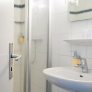 ein weißes Bad mit einem Waschbecken und einer Dusche in der Unterkunft Landhotel Bodensee in Konstanz