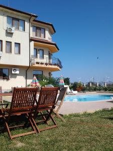 a building with two chairs next to a swimming pool at Guest House Golden Flake 4km from Bolata beach in Bŭlgarevo