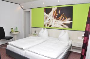 a bedroom with a white bed and a green wall at Hotel Garni Forellenfischer in Blaubeuren