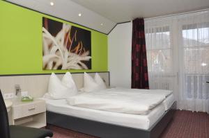 
a bedroom with a white bed and white walls at Hotel Garni Forellenfischer in Blaubeuren
