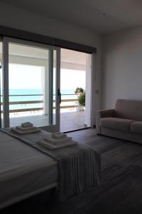 - une chambre avec un lit, un canapé et une grande fenêtre dans l'établissement Home Holiday Punta Piccola, à Porto Empedocle