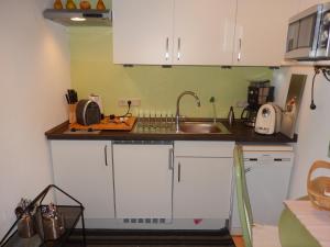 a kitchen with white cabinets and a sink at Apartment Altes Winzerhaus in Osann-Monzel