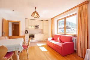 a living room with a red couch and a table at Appartements Strobl in Hopfgarten im Brixental