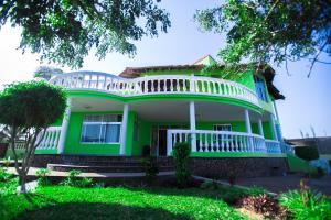 uma casa verde e branca com uma varanda branca em Bilene Beach House em Vila Praia do Bilene
