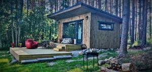 a small cabin in the woods with a wooden deck at Brīvdienu namiņš in Salacgrīva