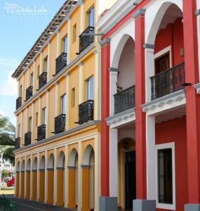 un edificio amarillo y rojo con balcones en una calle en Hotel Posada Doña Lala, en Tlacotalpan