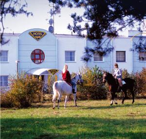 two people riding horses in front of a white building at Wellness Hotel Staré Město in Uherské Hradiště