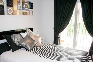 a bed with black and white pillows and a window at Residencial Linnea Sol by Mar Holidays in Playas de Orihuela