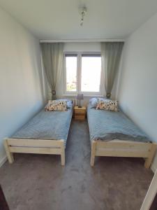 two beds in a room with a window at Mieszkanie z dobrą energią in Giżycko