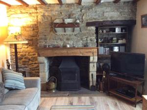 a living room with a stone fireplace and a television at Beech croft holiday cottage in Castleton