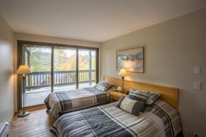 two beds in a bedroom with a balcony at Distinctive 4 bedroom townhouse, with outdoor hot tub minutes from the slopes Winterberry 4 in Killington