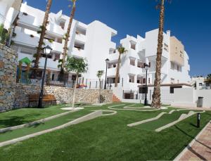 a courtyard with palm trees and a white building at Residencial Linnea Sol by Mar Holidays in Playas de Orihuela