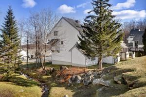 a white house with a tree and a creek at Ski on ski off, conveniently located, 2 bedroom condo with beautiful views, access to indoor pool Sunrise B3 in Killington