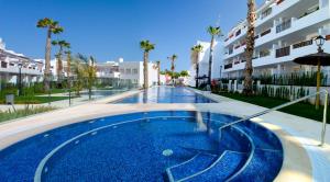 a swimming pool in a resort with palm trees and buildings at Residencial Linnea Sol by Mar Holidays in Playas de Orihuela