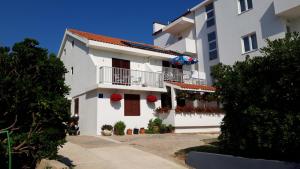 een wit appartementencomplex met bloemen op de balkons bij Apartments Magdalena in Pag