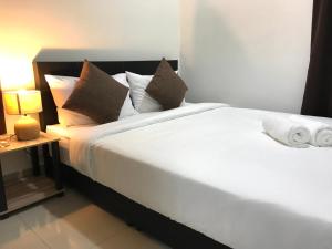 1 dormitorio con 1 cama con sábanas y almohadas blancas en Fabulous Mutiara Ville Cyberjaya en Cyberjaya