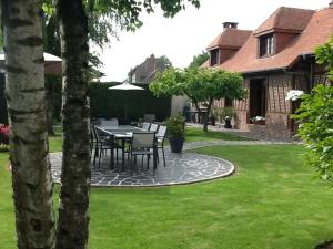 a patio with a table and chairs in a yard at Les Chambres de Paule in Thieulloy-lʼAbbaye