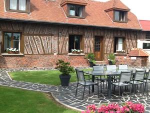 a patio with a table and chairs in front of a building at Les Chambres de Paule in Thieulloy-lʼAbbaye