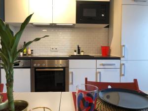 a kitchen with white cabinets and a table with a plant at Brexit getaway Studio in Luxembourg (Esch-Belval) in Esch-sur-Alzette