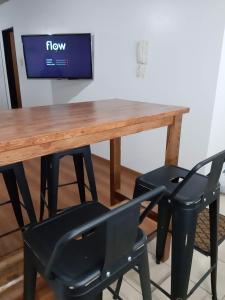 a wooden table with two black chairs and a television at Depto calle 20 y 37 - monoambiente, muy bonito y luminoso! in La Plata