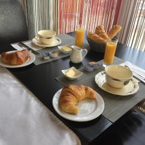 a black table with croissants and coffee and orange juice at Hôtel Restaurant Au Coucou in Pulversheim