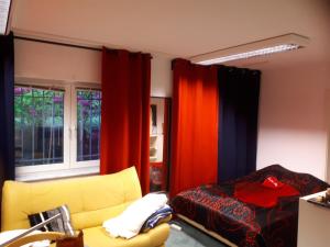 a bedroom with a yellow couch and red curtains at 4you in Berlin