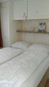two white beds in a room with a sign on the wall at Chalet Seazon O1 in Buren