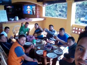 een groep mannen die rond een tafel zitten bij Hotel Don Chema in San Pedro La Laguna