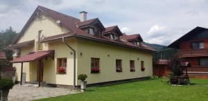 a white house with a brown roof and a yard at Penzion HACIENDA in Liptovská Osada