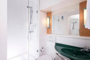 ein Badezimmer mit einem grünen Waschbecken und einer Dusche in der Unterkunft ibis Berlin City Nord in Berlin