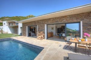 a house with a swimming pool and a dining table at U Sole Castellare in Pietracorbara