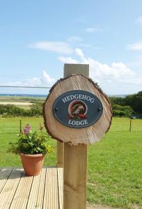 un cartello su una base di legno in un campo di Lilly's Lodges Orkney Hedgehog Lodge a Finstown