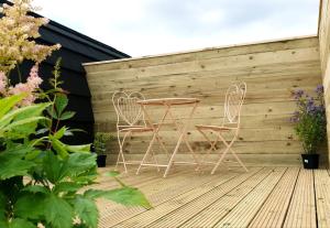 twee stoelen en een tafel op een houten terras bij Lilly's Lodges Orkney Hedgehog Lodge in Finstown