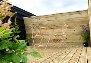 two chairs and a table on a wooden deck at Lilly's Lodges Orkney Hedgehog Lodge in Finstown