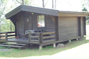 a log cabin with a porch and a window at Lidens Stugby in Vaggeryd